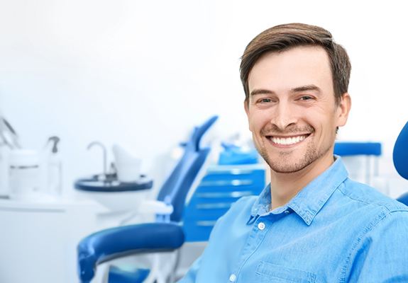 Man with blue shirt smiling in dental chair