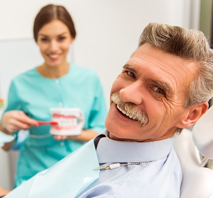 An older man smiling while visiting with his dental hygienist during a regular checkup
