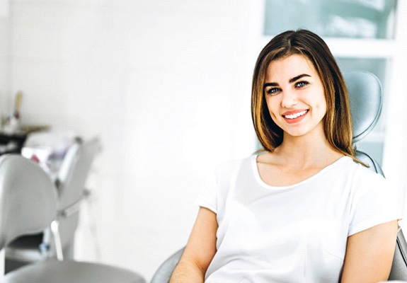 Woman in white shirt smiling in dental chair